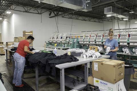 two people packing up clothing items after being embroidered